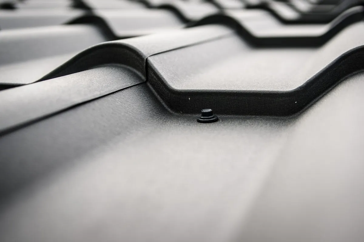 Close-up of a black steel roof featuring prominent rivets and tiles, illustrating roofing materials.