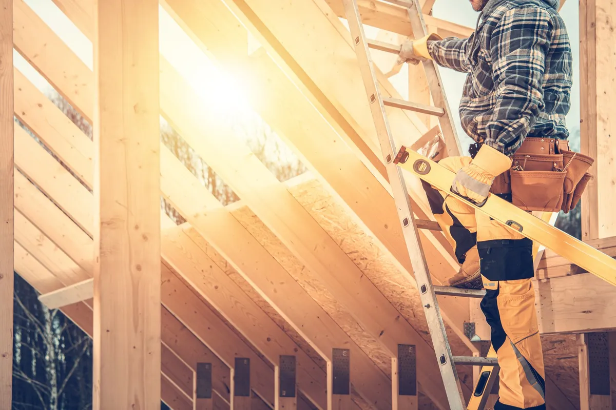 A construction contractor checks a level on a roof, emphasizing the importance of quality in roofing work.